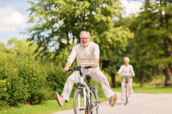 Älterer Mann fährt mit einem Fahrrad durch den Park und hat Spaß.
