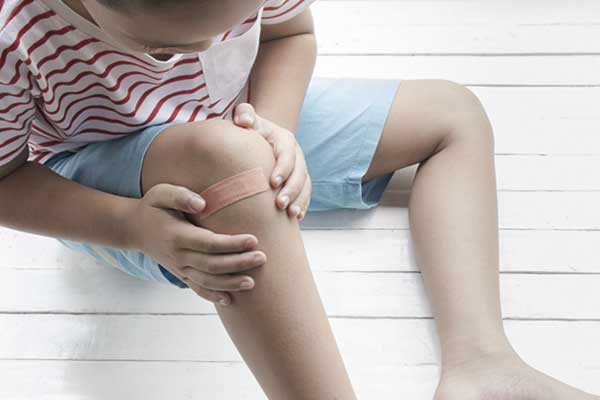 Ein Kind schaut sich sein verletztes Knie an.