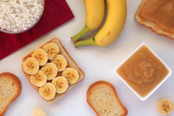 Lebensmittel bei Durchfall Tisch mit mehreren Lebensmitteln wie Bananen, Brot, Reis und Apfelmus
