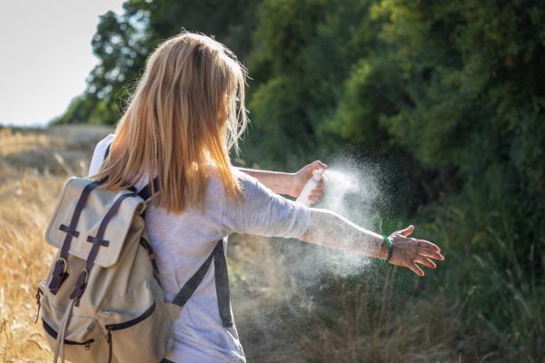 Eine Frau schützt sich mit Insektenspray gegen Zecken
