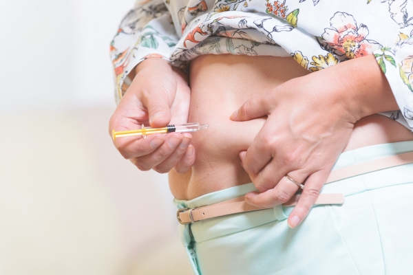 Frau spritzt sich Heparin in den Bauch. Frau spritzt sich Heparin in den Bauch.