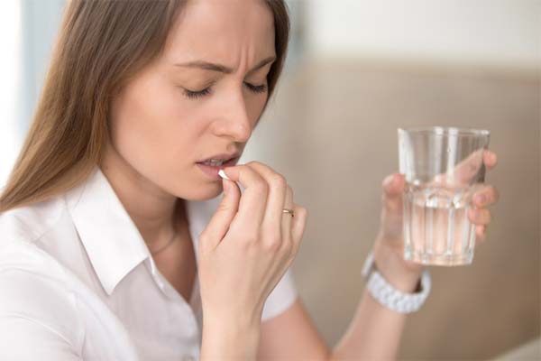 Eine Frau schluckt eine Migränetablette. Eine Frau schluckt eine Migränetablette.