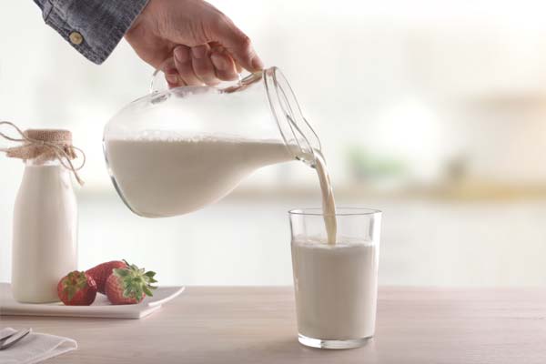 Eine Person schenkt Milch in ein Glas ein.