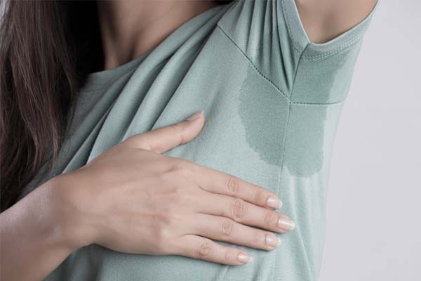 Eine braunhaarige Frau hat einen Schweißfleck am T-shirt Eine braunhaarige Frau hat einen Schweißfleck am T-shirt.