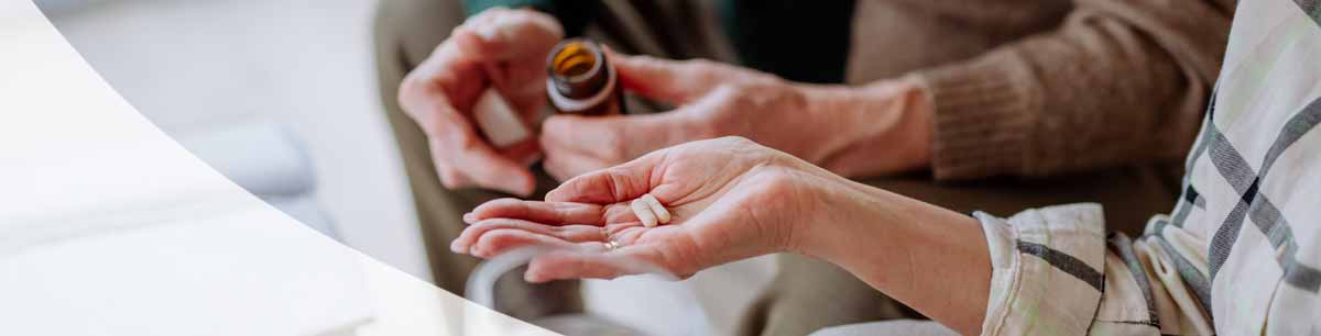 Eine offene Hand mit Kapslen und eine weitere die mit der Verpackung hilft Eine offene Hand mit Kapslen und eine weitere die mit der Verpackung hilft