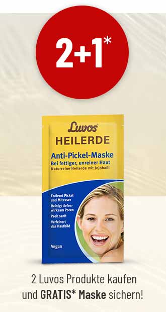 Luvos Heilerde Anti-Pickel-Maske vor hellem Hintergrund. Darüber ein roter Kreis mit der weißen Aufschrift „2+1*“. Darunter steht ein Hinweis auf eine Gratis-Maske beim Kauf von zwei Produkten.