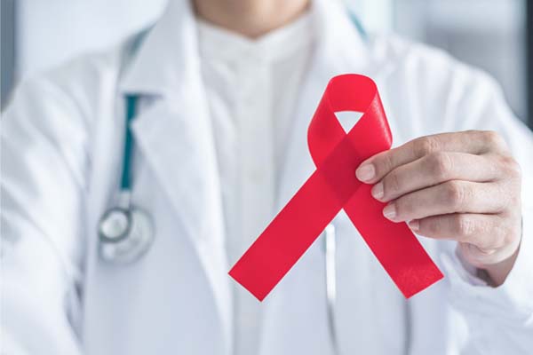 Ein Arzt zeigt eine rote Aids-Schleife