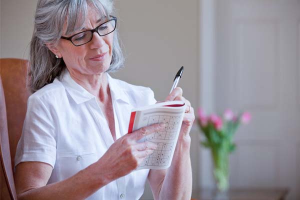 Eine ältere Frau mit grauen Haaren schreibt etwas auf einen Notizblock.