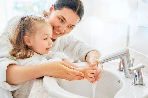 Eine Mutter zeigt ihrer Tochter, wie sie sich richtig die Hände wäscht.