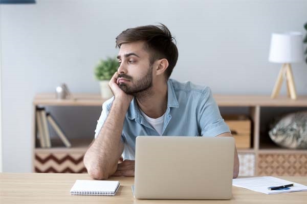 Ein Mann sitzt unkonzentriert vor seinem Laptop.