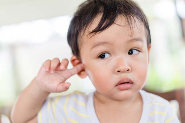 Ein Kind zeigt auf sein Ohr, weil es Ohremschmerzen hat.