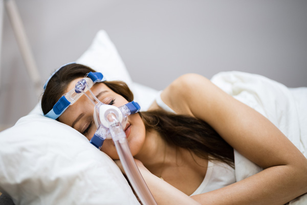Eine Frau schläft mit einer CPAP-Maske.