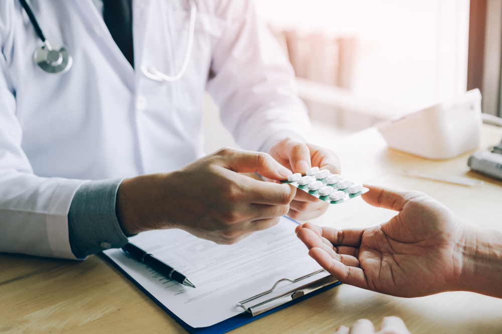 Ein Arzt gibt einem Patienten einen Blister mit Antibiotika-Tabletten.