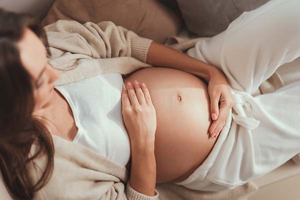 Schwangere Frau liegt und hält ihren Bauch. Schwangere Frau liegt und hält ihren Bauch.