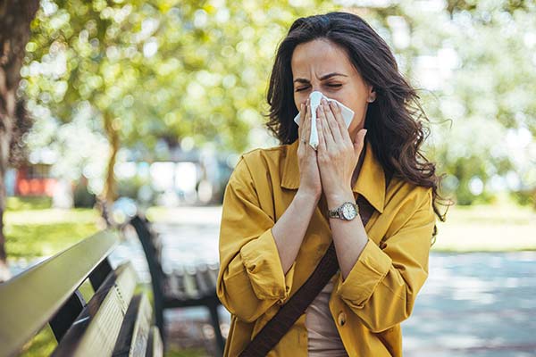 Frau niest in ein Taschentuch im Freien. Frau niest in ein Taschentuch im Freien.