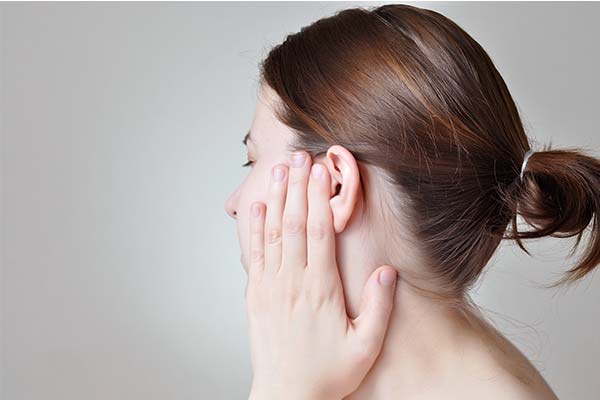 Frau hält sich die Hand ans Ohr wegen Ohrenschmerzen oder Ohrenschmalz. Frau hält sich die Hand ans Ohr wegen Ohrenschmerzen oder Ohrenschmalz.