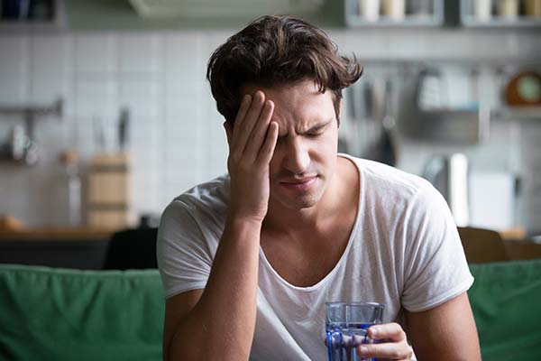 Mann mit Kopfschmerzen hält ein Glas Wasser. Mann mit Kopfschmerzen hält ein Glas Wasser.