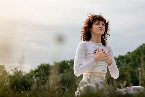 Junge Frau bei einer achtsamen Entspannungsübung in der Natur zur Stressbewältigung. Junge Frau bei einer achtsamen Entspannungsübung in der Natur zur Stressbewältigung.