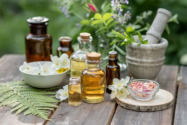Gläser mit Ölen, Mörser und weiße Blüten für selbstgemachte Naturkosmetik auf Holztisch. Gläser mit Ölen, Mörser und weiße Blüten für selbstgemachte Naturkosmetik auf Holztisch.