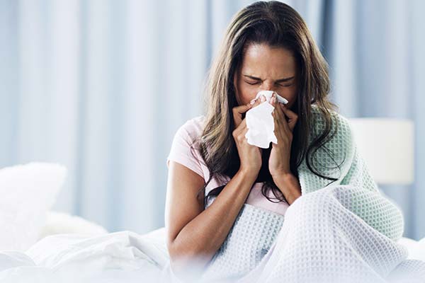 Frau mit Symptomen einer Sinusitis und verstopfter Nase nutzt ein Taschentuch im Bett. Frau mit Symptomen einer Sinusitis und verstopfter Nase nutzt ein Taschentuch im Bett.