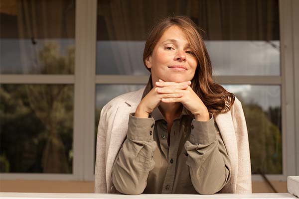 Lächelnde Frau in Business-Kleidung vor einem hellen Fenster. Lächelnde Frau in Business-Kleidung vor einem hellen Fenster.