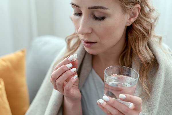 Frau betrachtet Tablette und hält ein Glas Wasser. Frau betrachtet Tablette und hält ein Glas Wasser.