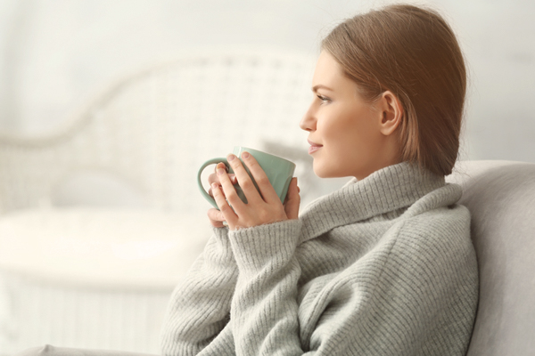 Eine Frau hält eine Tasse warmen Tee in ihren Händen.